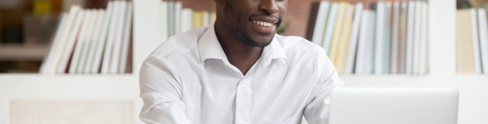 Smiling millennial african american businessman typing working on laptop in office, happy black male student worker using e learning apps study online doing research on computer, internet education